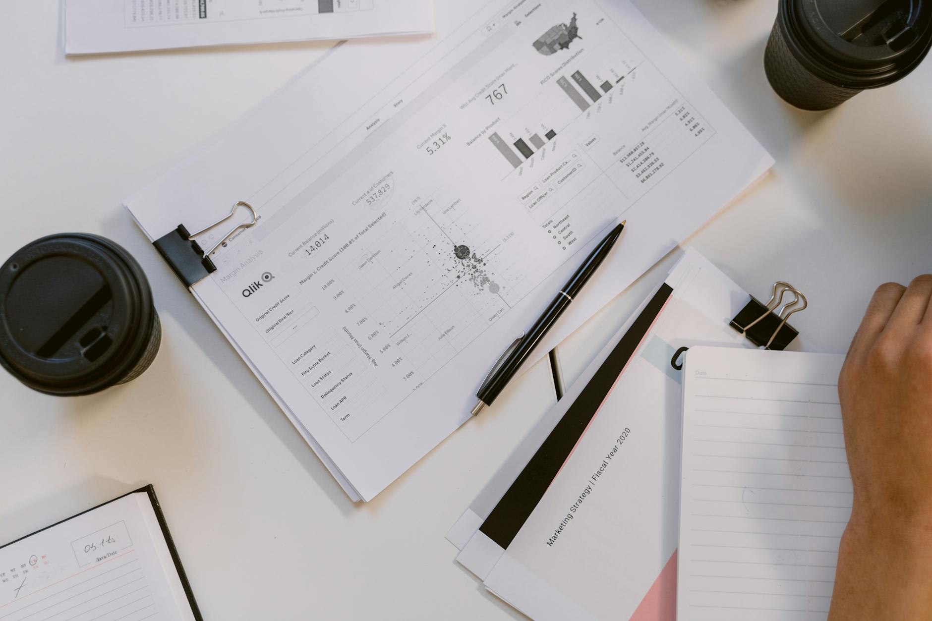 Overhead view of business reports and charts in a modern office setup on a white table.