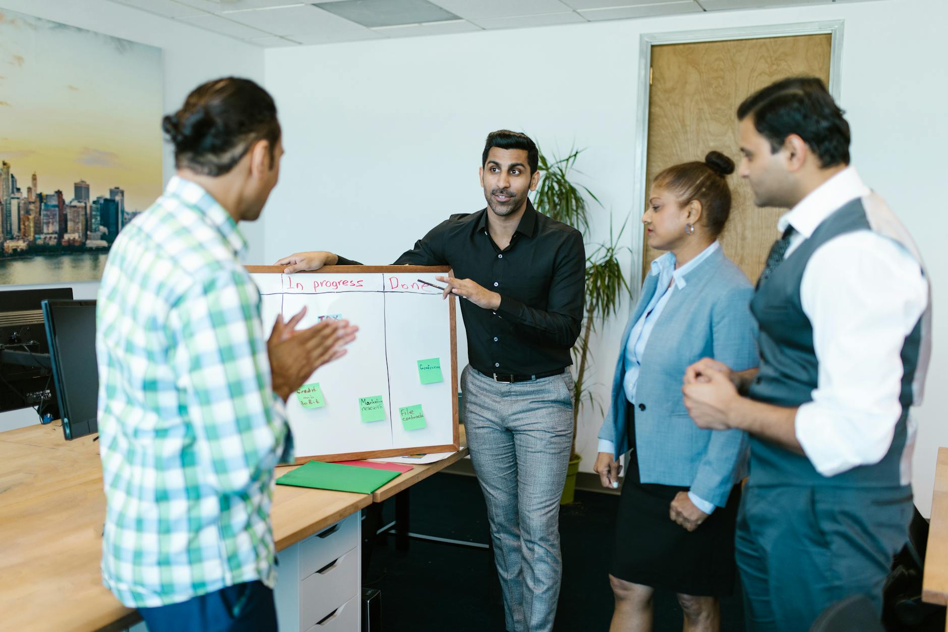 Diverse team discussing project progress with a board in a modern office.