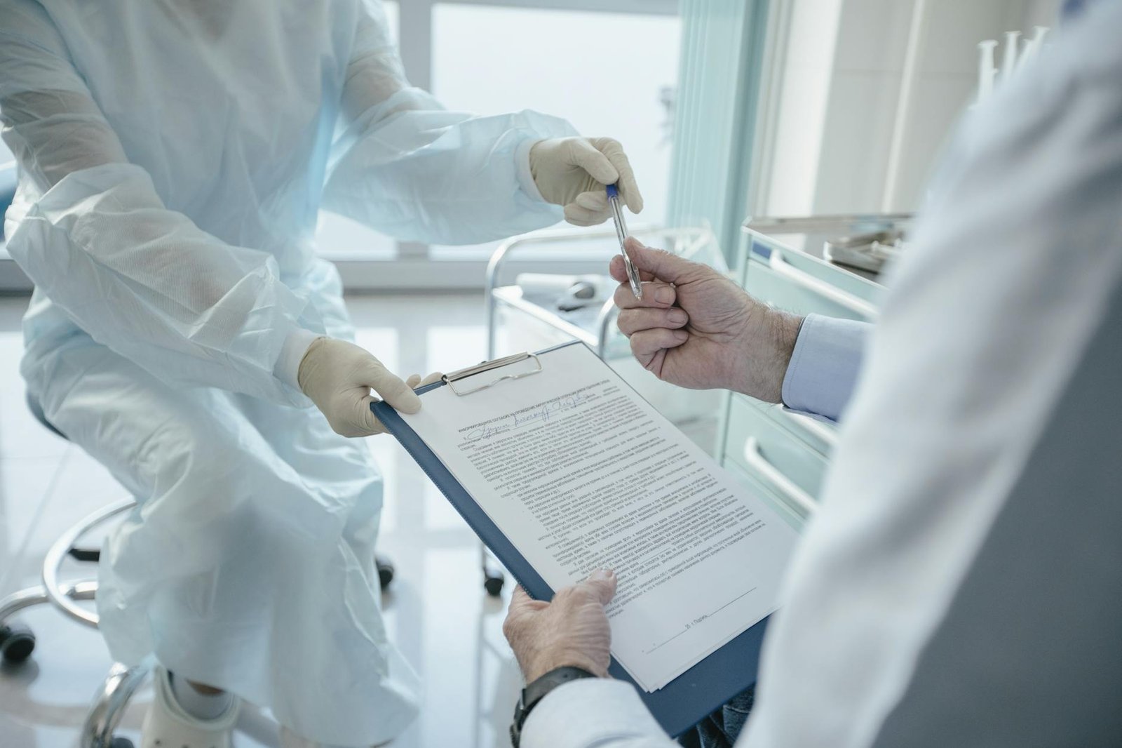 A doctor hands a clipboard to a patient for signature
