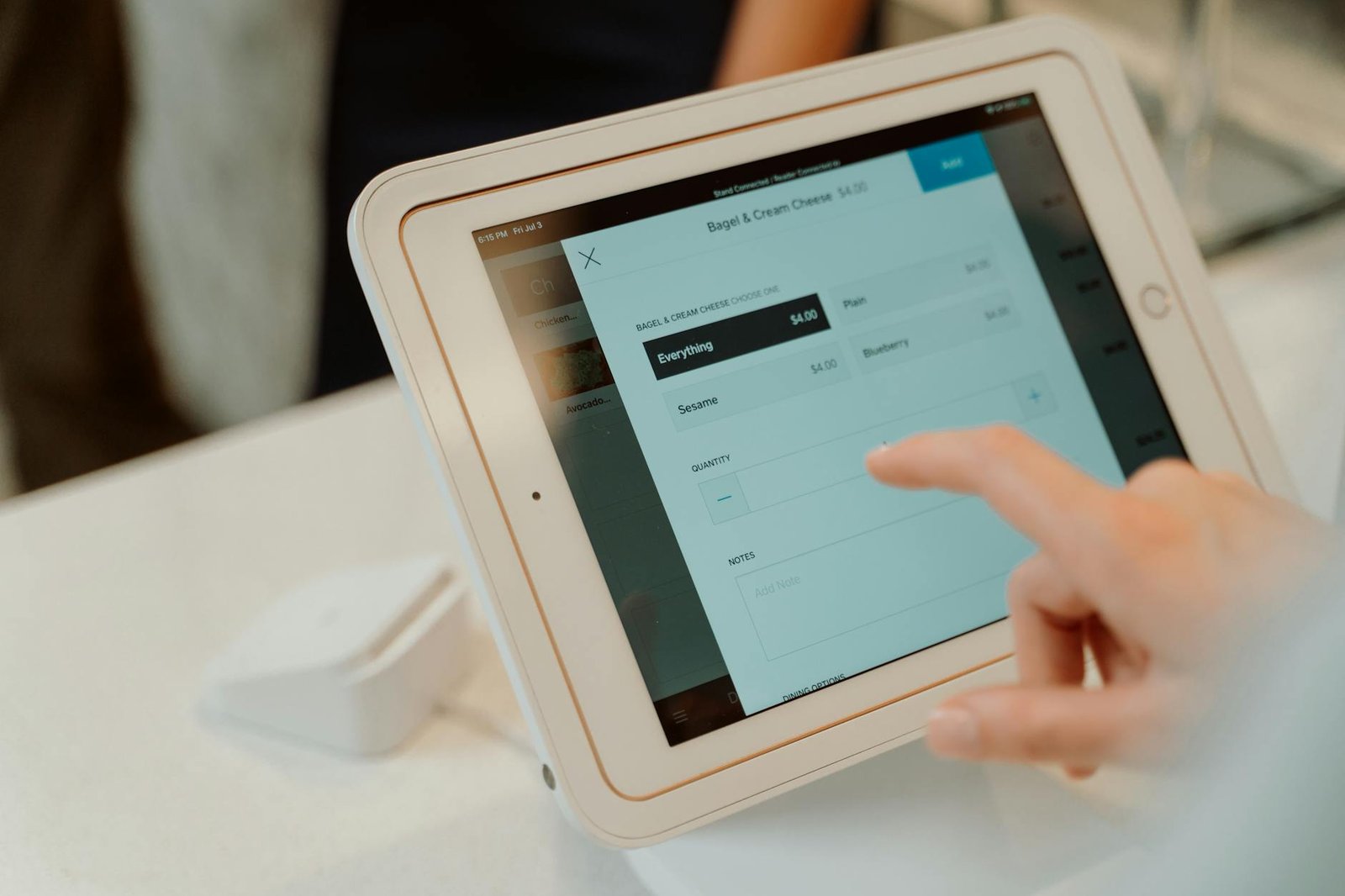 A person uses a tablet-based point-of-sale system by selecting options on a touchscreen device.