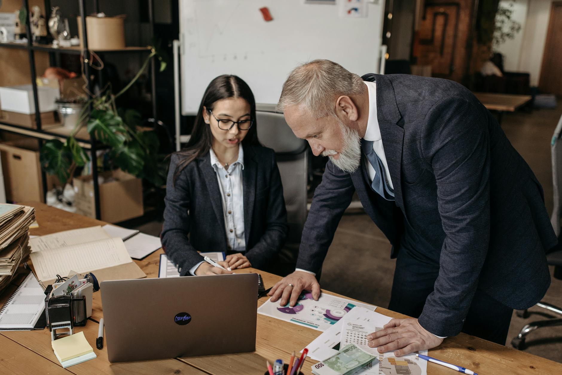 Business meeting with two professionals discussing charts and data at a desk.