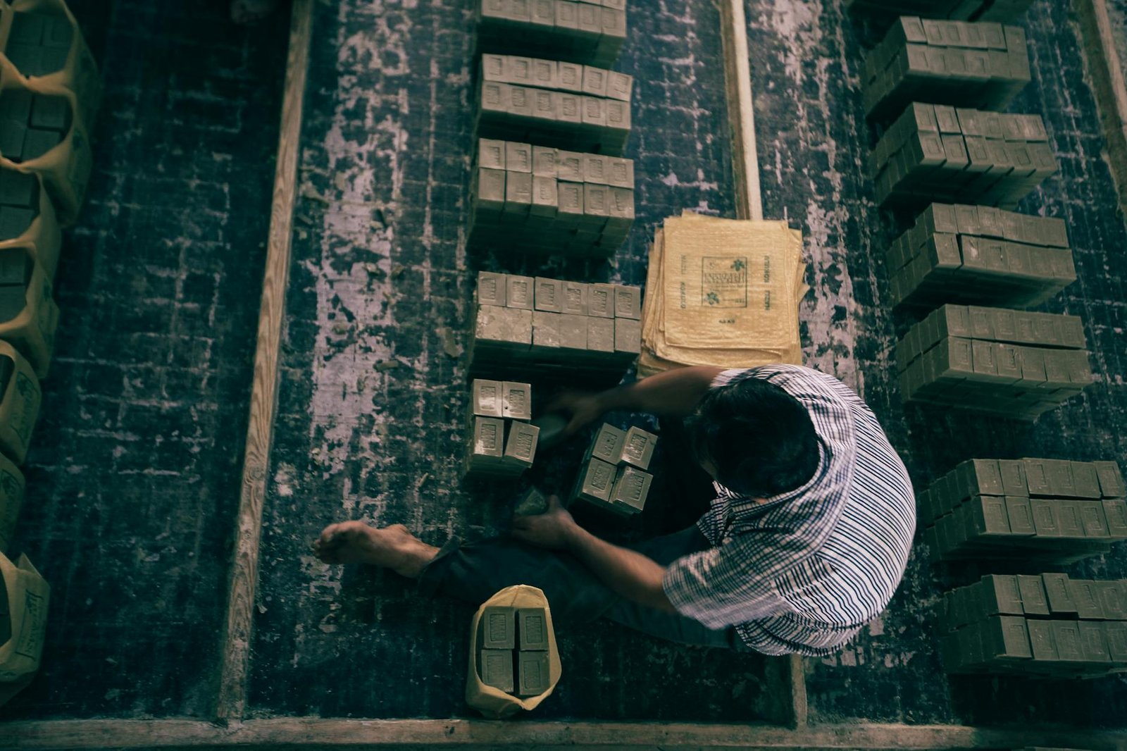 An overhead view of a worker processing soap packages in a traditional factory setting.