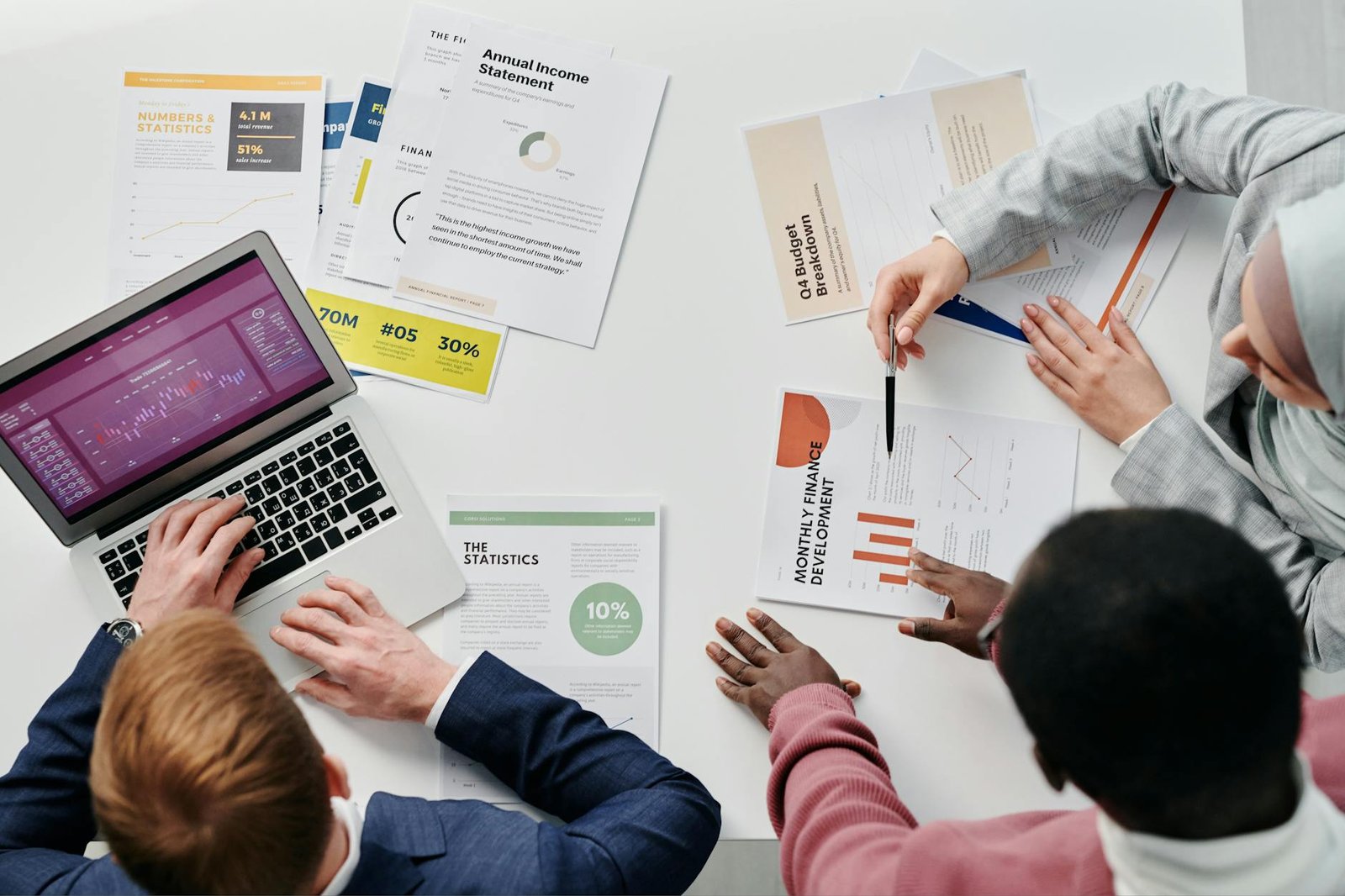 Business meeting with professionals discussing financial reports and graphs at a work desk.