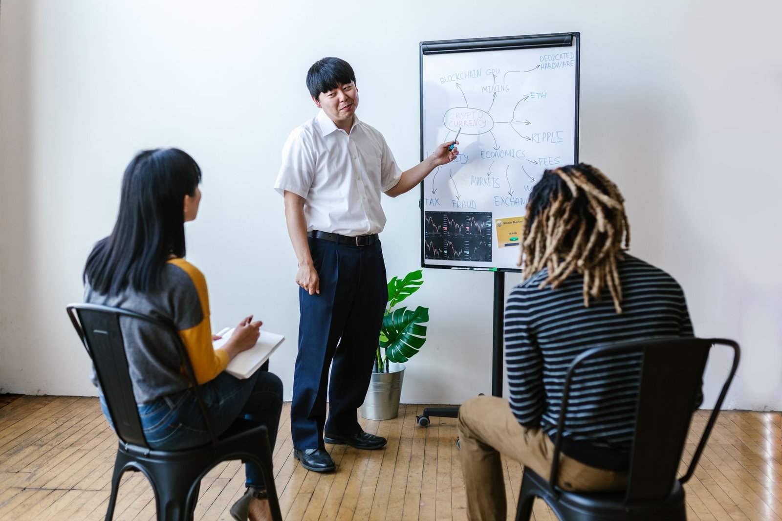 Three people in an indoor meeting discussing cryptocurrency and blockchain strategies.