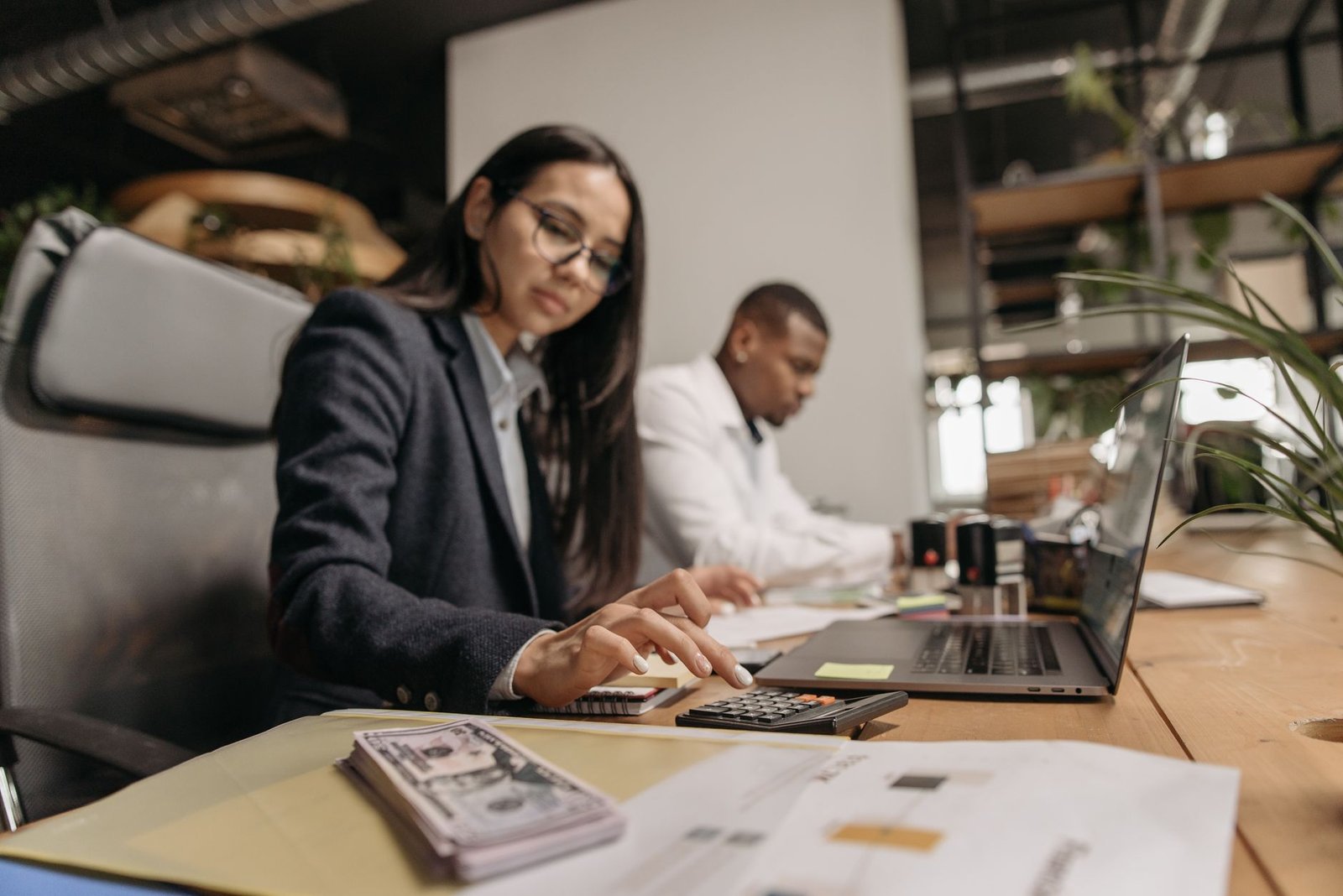 Two business professionals collaborating with a laptop and calculator in a modern office.
