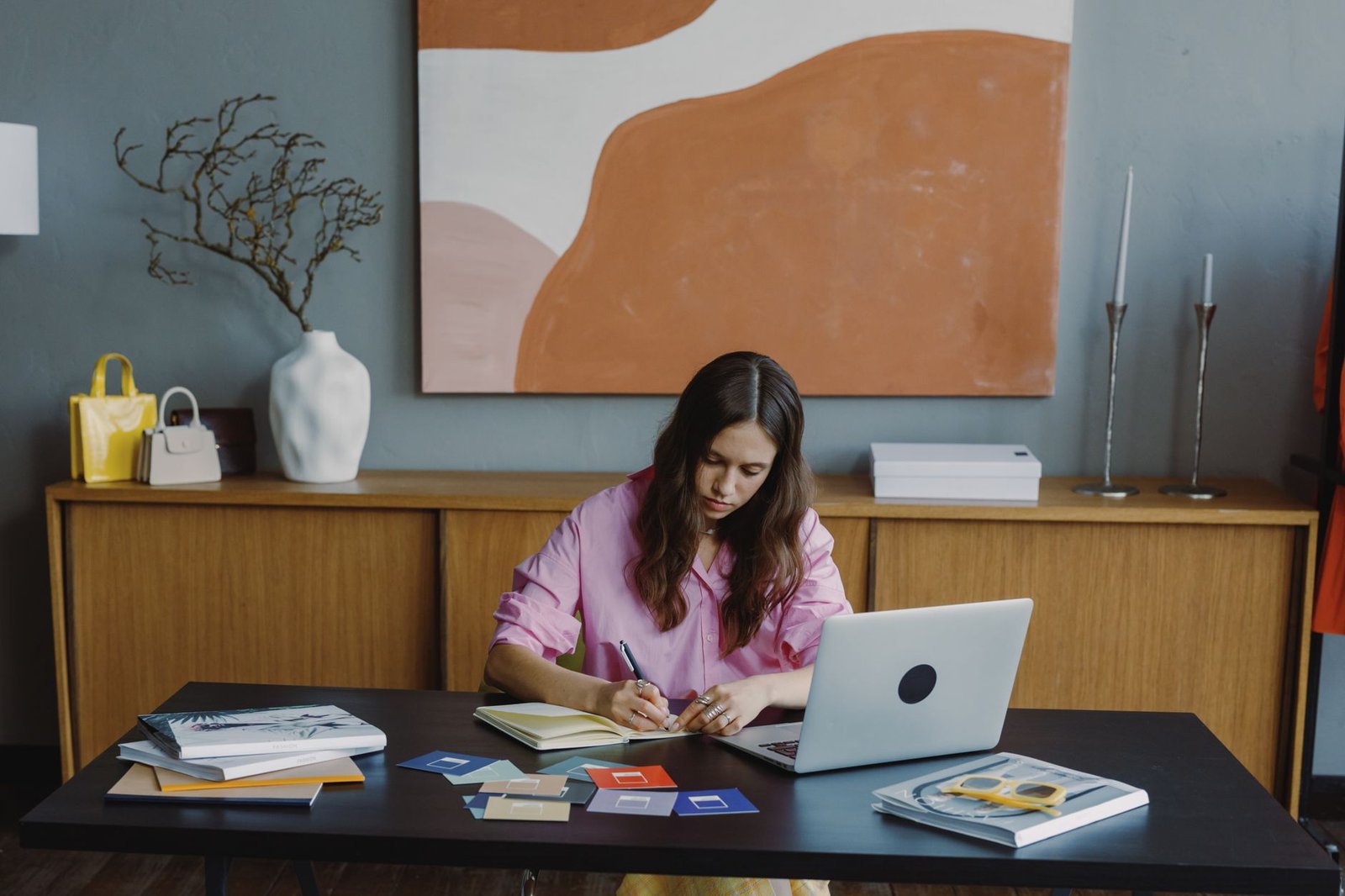 Woman working remotely at home office on a design project with laptop and color swatches.